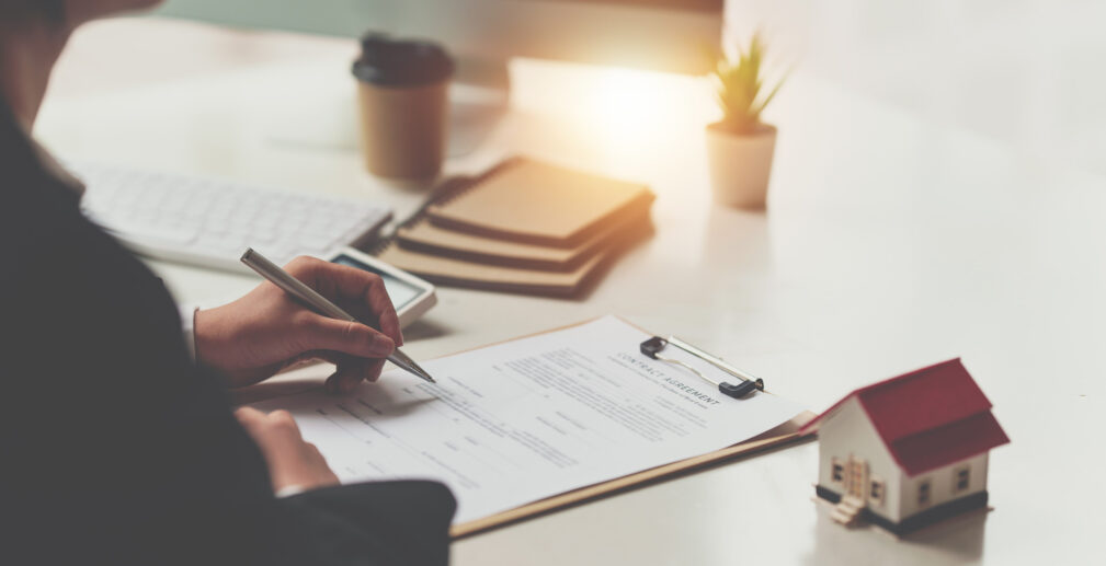 Close up of Business woman pointing and signing agreement for buying house. Bank manager concept