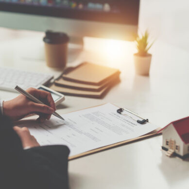 Close up of Business woman pointing and signing agreement for buying house. Bank manager concept