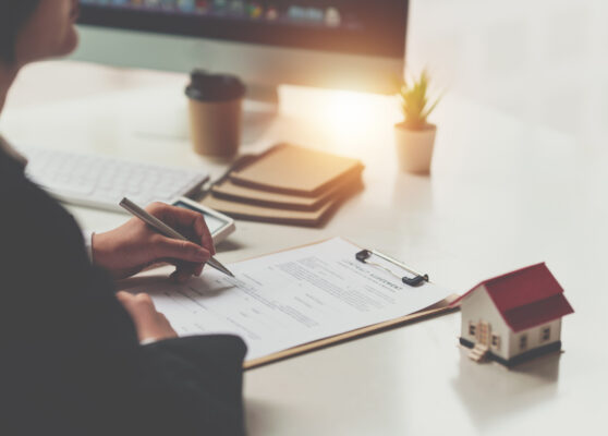 Close up of Business woman pointing and signing agreement for buying house. Bank manager concept